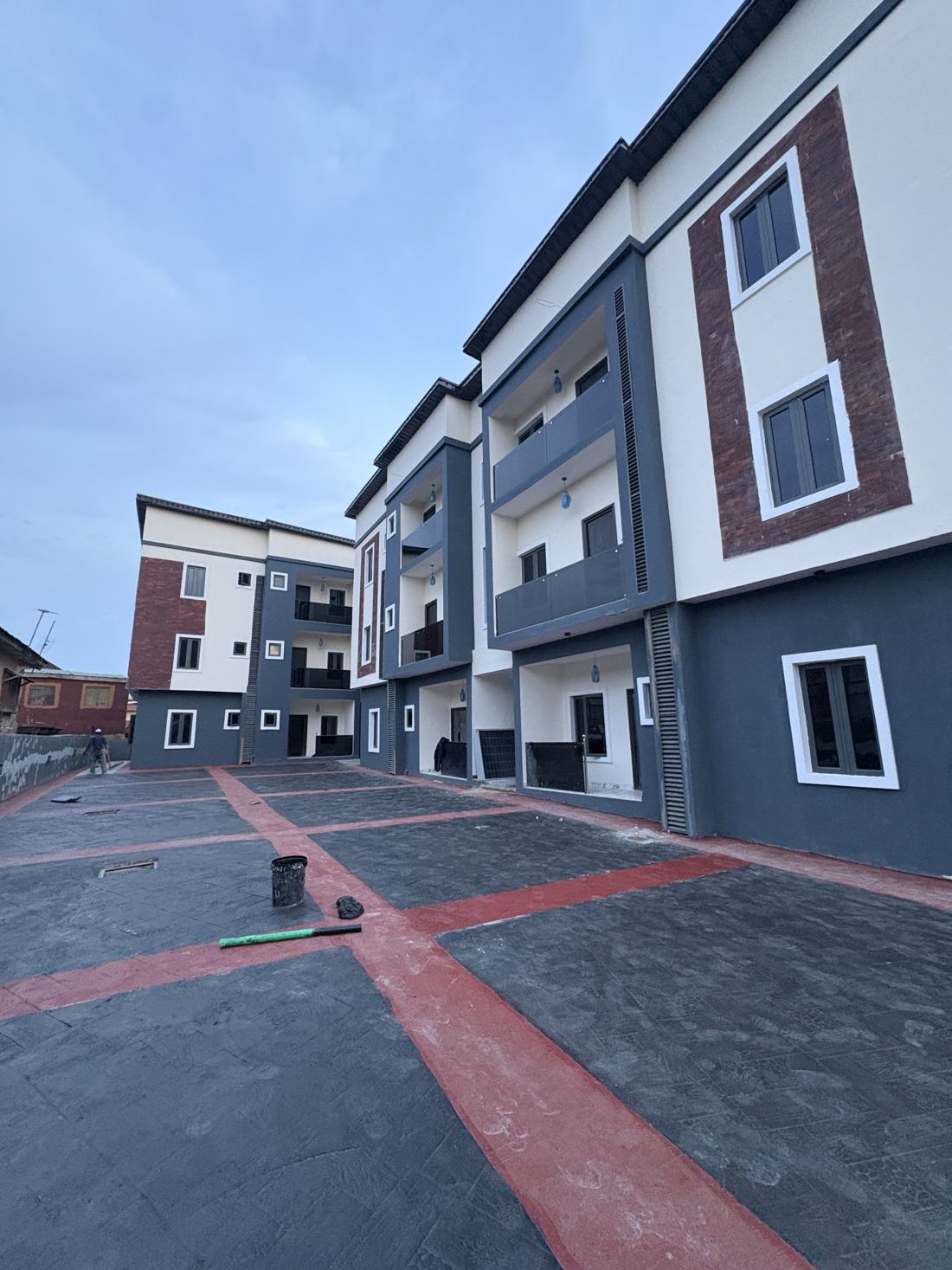 Exterior of the finished three-storey block with balconies and stamped-concrete courtyard